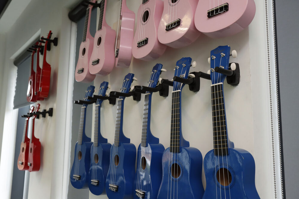 Ukeleles in red, blue and pink adorn the walls of the music room