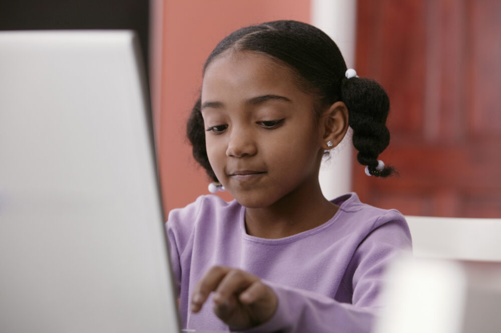 A young girl pupil uses a laptop at her desk