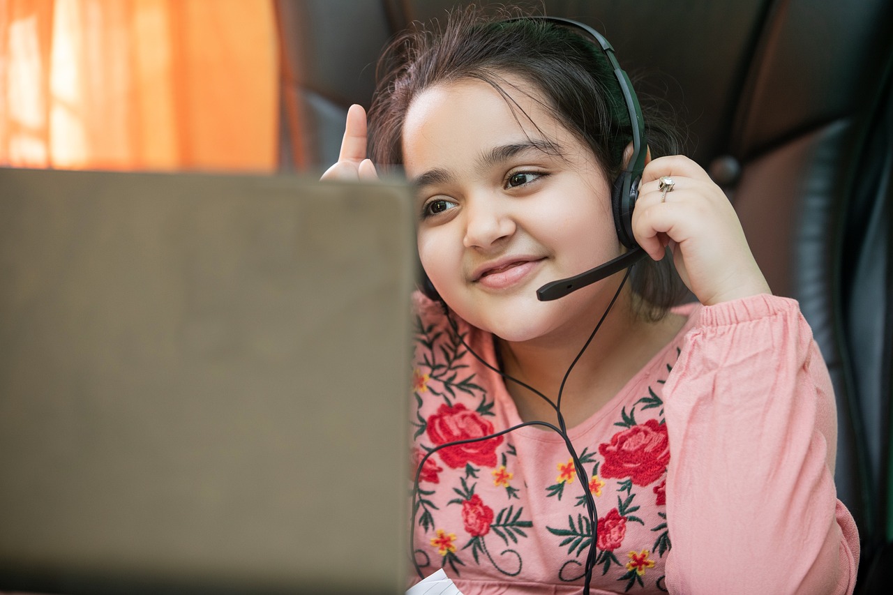 A smiling child wearing a headset participates in an online lesson