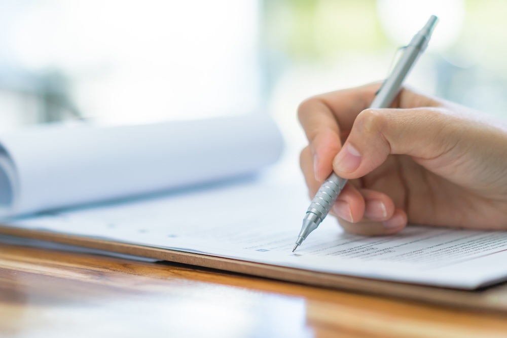 Hand with pen over application form .