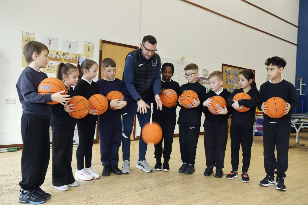 A group of pupils and a teacher holding basketballs