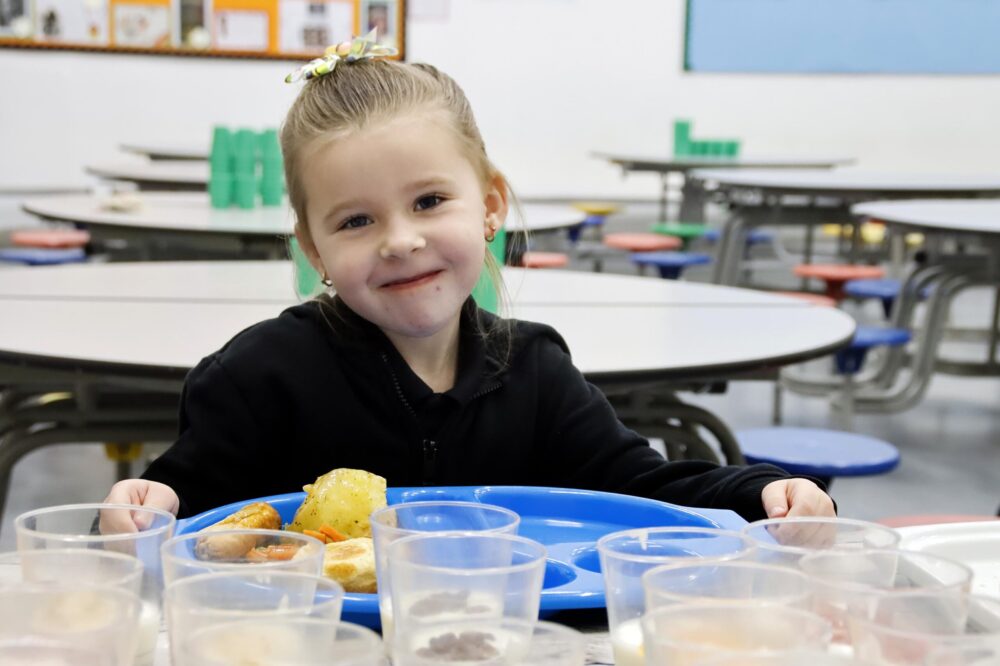 Young girl holding a dinner tray